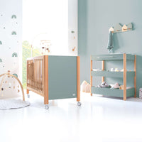 Habitación pequeña para bebés con cuna y cambiador en madera/verde-oliva